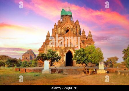 Farbenfrohe blaue und rote sunrise Himmel über alte buddhistische Tempel von grüner Vegetation im Old Bagan, Myanmar umgeben. Stockfoto