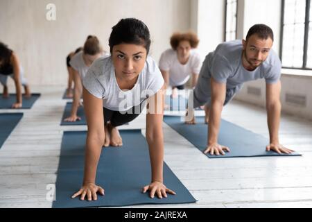 Unterschiedliche Menschen üben Yoga in der Gruppe Lektion, Plank Übung Stockfoto