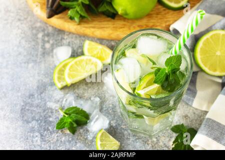 Frischen Mojito Cocktail mit Kalk, Eis und Minze im Glas auf einem grauen Stein. Sommer kalte Getränke und Cocktails. Stockfoto