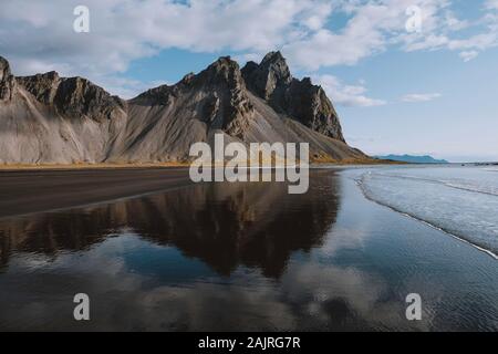 Dramatischer blauer Himmel und Bergreflexion am Strand in Island Stockfoto