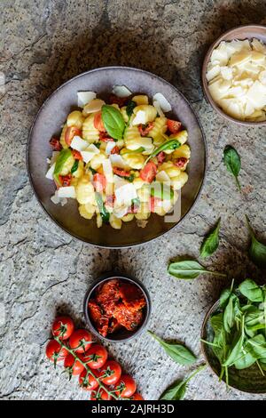 Kalorienarme gnocchi Pasta Salat mit frischen und gedünsteten Spinat, sonnengetrocknete Tomaten und Parmesankäse Stockfoto