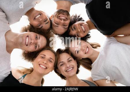 Low Angle Lächeln unterschiedlichen Menschen im Kreis stehend, Erfolg feiern. Stockfoto