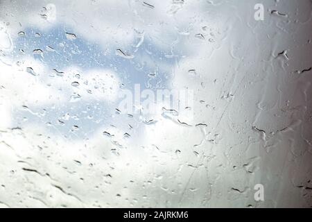 Autofenster mit Regentropfen. Fahren bei Regen. Wetterhintergrund. Regnerisches Glas. Stockfoto