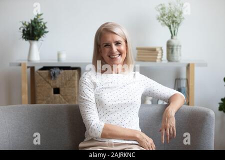 Headshot von lächelnden reife Frau zu Hause couch posiert Stockfoto