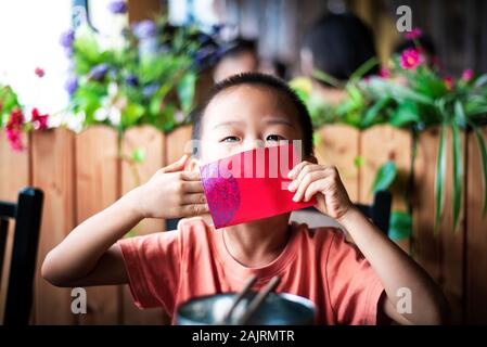 Chinesischer junge Die rote Tasche auf dem Esstisch Stockfoto