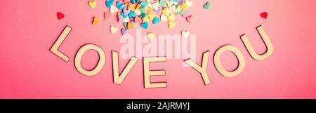 Happy Valentinstag. Schöne Karte mit bunten Herzen Bonbons auf rosa Hintergrund. Februar Urlaub. Holz- wörter Buchstaben sagen Liebe dich. Web Banne Stockfoto