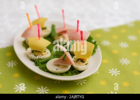 Kinder Nahrung in Form von Schiffen. Kreative Sandwiches von Eiern, die in der Form der Schiffe. Kindermenü auf grünem Hintergrund. Stockfoto