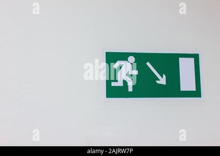 Grüne Notausgangsplatte an der weißen Wand Stockfoto