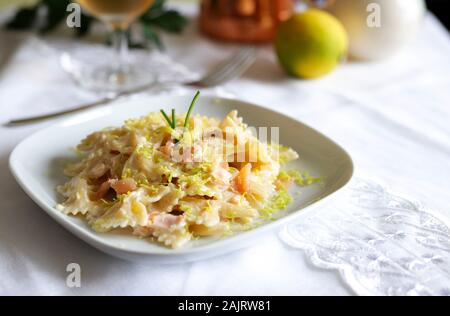 Farfalle Pasta mit Räucherlachs, Sahnesauce und Zitrone auf weiße Platte. Stockfoto