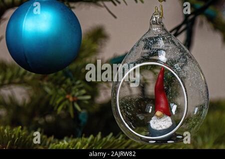 Weihnachtsschmuck, Blau Christbaumkugel und Santa's Elf in einer Kugel, die an einem Baum hängend Stockfoto