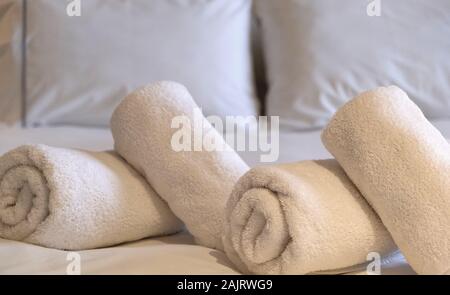 Hotel Handtücher. Weißen flauschigen, gewalzt, Handtücher, Bettwäsche und Kissen auf dem Bett, Schlafzimmer Interior Detail. Nähe zu sehen. Stockfoto