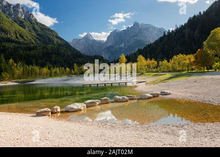 Die alpinen See Jasna mit großen Felsen im Wasser und von Bäumen im Herbst Farben und Alpen Berge in der Nähe von Kranjska Gora in Slowenien umgeben. Stockfoto