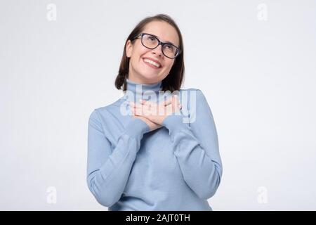 Freut mich, Frau Kollegin hält die Hand auf die Brust zufrieden sein Kompliment von Fremden zu hören. Studio shot Stockfoto