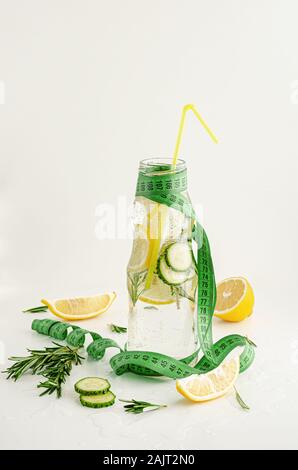 Maßband und eine Flasche detox Wasser mit Zitrone, Gurke und Rosmarin. Gewicht Verlust und gesunden Lebensstil Konzept Stockfoto