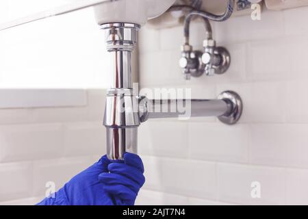 Klempner Reparaturen und pflegt Chrom Düker unter dem Waschbecken. Klempner in Bad, Sanitär-Konzept zusammen- und einbauen Stockfoto