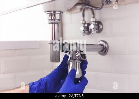 Klempner Reparaturen und pflegt Chrom Düker unter dem Waschbecken. Klempner in Bad, Sanitär-Konzept zusammen- und einbauen Stockfoto