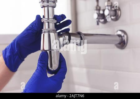 Klempner Reparaturen und pflegt Chrom Düker unter dem Waschbecken. Klempner in Bad, Sanitär-Konzept zusammen- und einbauen Stockfoto