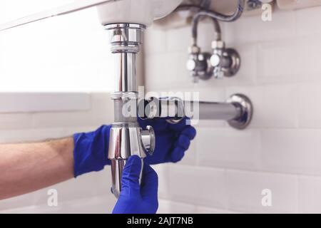 Klempner Reparaturen und pflegt Chrom Düker unter dem Waschbecken. Klempner in Bad, Sanitär-Konzept zusammen- und einbauen Stockfoto