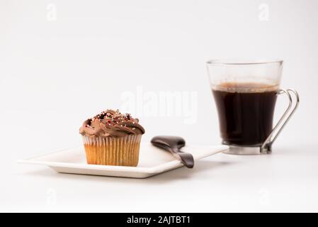 Chocolate Muffins auf weißem Hintergrund mit einer Tasse Kaffee und Löffel aus Holz. Hausgemachte Backen, selektiver Fokus, Nahaufnahme. Stockfoto