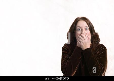 Porträt einer weißen Frau mittleren Alters schnappte mit Überraschung oder Angst allein auf weißem Hintergrund Stockfoto