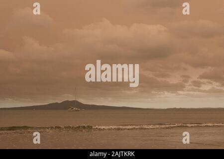 Neuseeland, Nordinsel - 5. Januar 2020: Die Ansicht von Dunst in den Himmel von Australiens Buschbrände hängt über Torbay Strand mit Rangitoto Island auf Ba Stockfoto