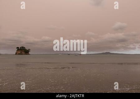 Neuseeland, Nordinsel - 5. Januar 2020: Die Ansicht von Dunst in den Himmel von Australiens Buschbrände hängt über Torbay Strand mit Rangitoto Island auf Ba Stockfoto