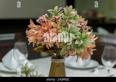 Kristallschalen, Stoff Servietten und dekorative Blumen in Vase auf einem Esstisch neben eine Kerze. Einfache Dekoration der Hochzeitstag. T Stockfoto