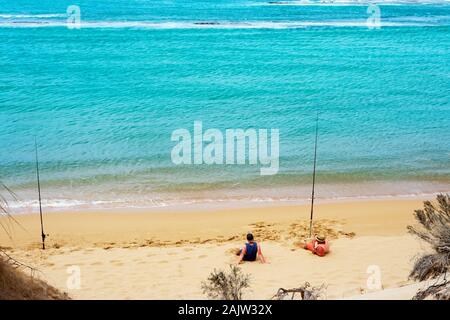 Ein Foto von zwei Männer entspannen am Strand mit Angelruten, genießen Sommer und jede andere Firma. Stockfoto