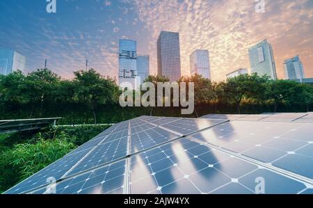 Ökologische Energie erneuerbare solar panel Anlage mit urbanen Landschaft Sehenswürdigkeiten im Sonnenuntergang Stockfoto