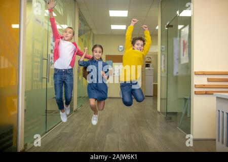 Fröhliche Kinder, die am Ende ihrer Unterrichtseinheiten froh Stockfoto