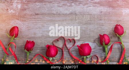 Rosen und Bänder Herzen auf alten Tisch. Valentinstag Hintergrund Stockfoto