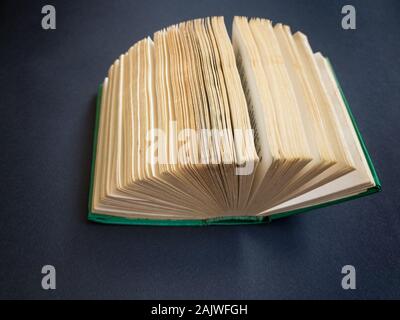 Draufsicht auf winzigen Buch liegen auf dunklem Papier Oberfläche wie ein Ventilator geöffnet Stockfoto
