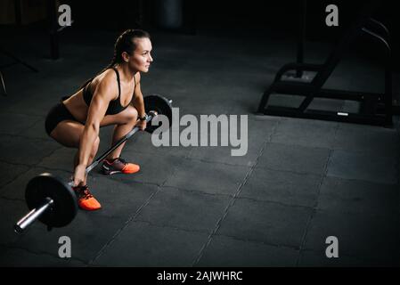 Athletische Frau bodybuilder Vorbereitung der schwere Hantel vom Boden zu heben Stockfoto