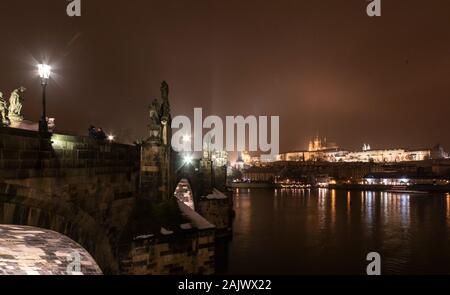 Die Karlsbrücke, Prag, im winter nacht mit barocken Statuen mit Moldau und die Prager Burg beleuchtet auf dem Hügel im Hintergrund Stockfoto