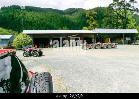 Red Quad Bikes aufgereiht außerhalb von Gebäuden im Cable Bay Adventure Park, in der Nähe von Hira, Nelson, Südinsel, Neuseeland. Stockfoto