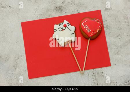 Gingerbread Cookies auf ein rotes Blatt für Valentines Tag. Gingerbread Cookies in Form einer Katze und ein Herz. Für Text, grauer Hintergrund Stockfoto