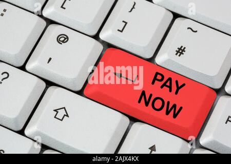 Eine Tastatur mit Pay Now in schwarzer Schrift auf einer roten ENTER-Taste. Online-Shopping, Internet-Kauf Zahlungskonzept. England, Großbritannien Stockfoto