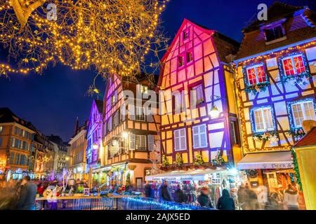 Colmar, Frankreich - 23 November 2019: Traditionelle beleuchtete Weihnachtsmarkt auf eine Straße der Altstadt in Colmar, Elsass. Weihnachtsmarkt in Colmar ist o Stockfoto