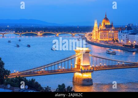 Die Stadt Budapest, Ungarn, die touristischen Boote Kreuzfahrt auf der Donau entlang der Kettenbrücke und dem Parlament Gebäude auf einem blauen Abend Stockfoto