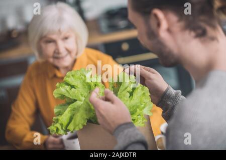 Junger Mann bei Grüns in seine Hände suchen Stockfoto