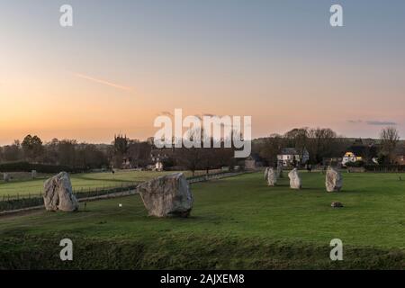 Avebury, Wiltshire, ein riesiges Neolithisches henge Monument gebaut um 3000 v. Chr.. Die beiden Portal Steine und ein Teil des inneren Kreises mit dem Dorf jenseits Stockfoto