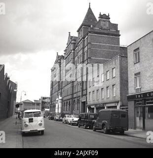 1960, historische Straße in Fulham, London, England, UK, anzeigen Arlington House, einem großen viktorianischen Haus, Garage, B&G Motoren und Autos und Lieferwagen des Era in der Straße geparkt. Stockfoto