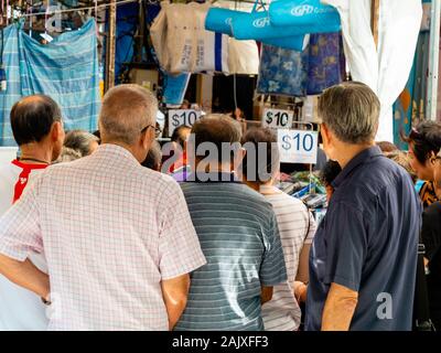 Singapur - 26 Dez 2019 - eine Masse von älteren Asiatischen chinesischen Pensionäre/Rentner/alte Menschen durchsuchen Sie eine Open-air-reduzierte Produkte Markt in Chinatow Stockfoto