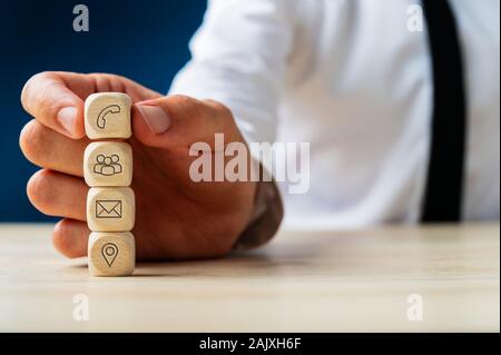 Kundendienstmitarbeiter stapeln Holz- Würfel mit Kontakt und Informationen Symbole auf Sie. Stockfoto