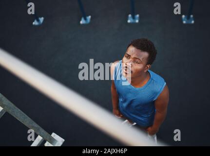 Eine Ansicht einer jungen afrikanischen amerikanischen männlichen Athleten bereitet Pull Ups auf horizontalen Balken - Mann Angst vor der Übung zu tun Stockfoto