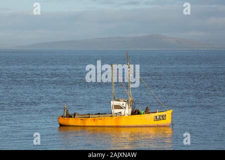 Ein Boot am Weihnachtstag günstig an der Küste von Morecambe mit Warton Crag im Hintergrund. Morecambe Lancashire England UK GB Stockfoto