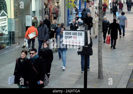 Paar einkaufen zu Weihnachten vorbei gehen Adam und Eva Gericht W1 street sign in der Oxford Street im West End von London England UK KATHY DEWITT Stockfoto