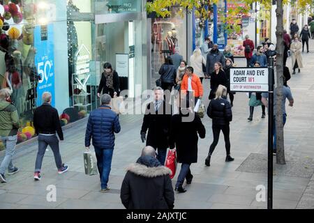 Käufer an Weihnachten vorbei gehen Adam und Eva Gericht W1 street sign in der Oxford Street im West End von London England UK KATHY DEWITT Stockfoto