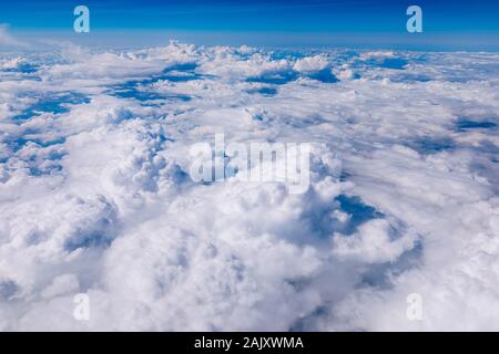 Erstaunlich, Wolken und Himmel durch das Fenster eines Flugzeugs zu sehen. Wolken, Sonne, Himmel, durch das Fenster eines Flugzeugs zu sehen. Der strahlend blaue Himmel mit Clo Stockfoto