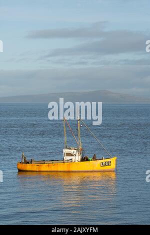 Ein Boot am Weihnachtstag günstig an der Küste von Morecambe mit Warton Crag im Hintergrund. Morecambe Lancashire England UK GB Stockfoto